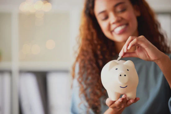 Image - Woman Putting Coins into a Piggy Bank